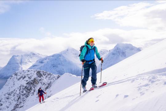 En person på vei opp fjellet å ski